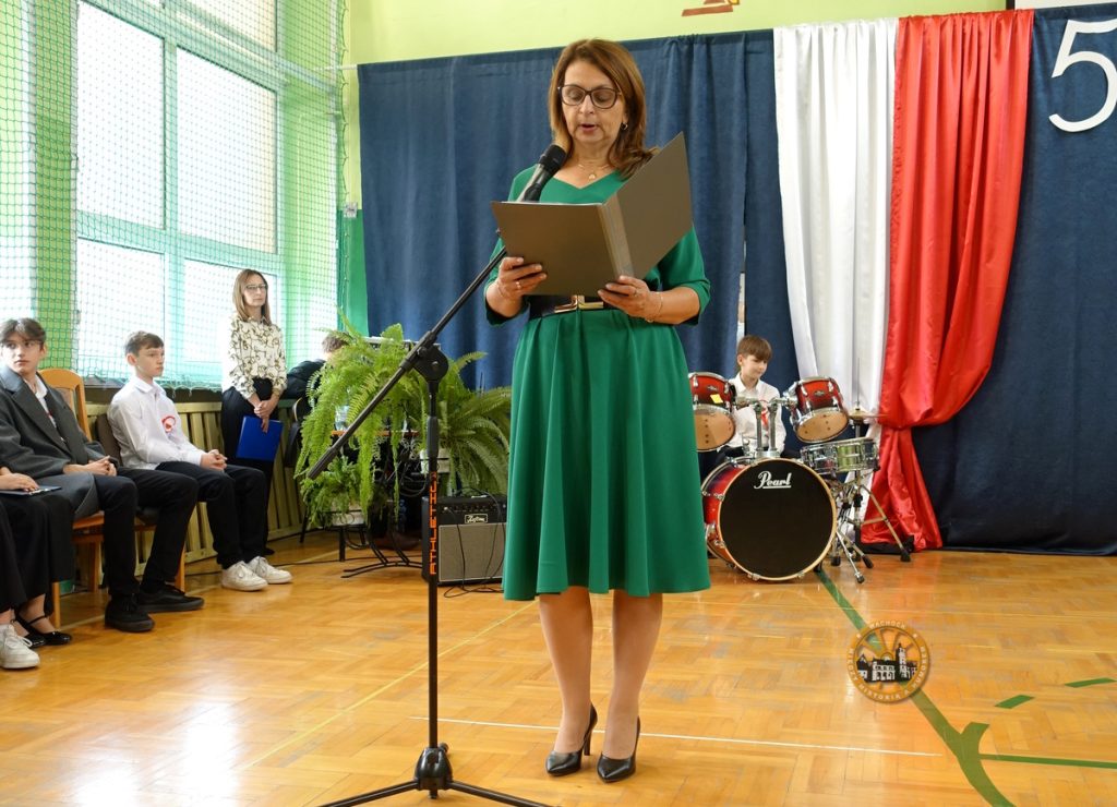 kobieta w zielonej sukience stoi przy mikrofonie i czyta 