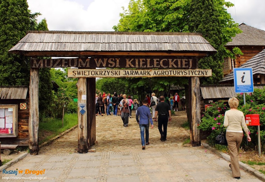Zdjęcie przedstawia bramę Muzeum Wsi Kieleckiej z wchodzącymi przez nią turystami. Nad wejściem napis: Świętokrzyski Jarmark Agroturystyczny