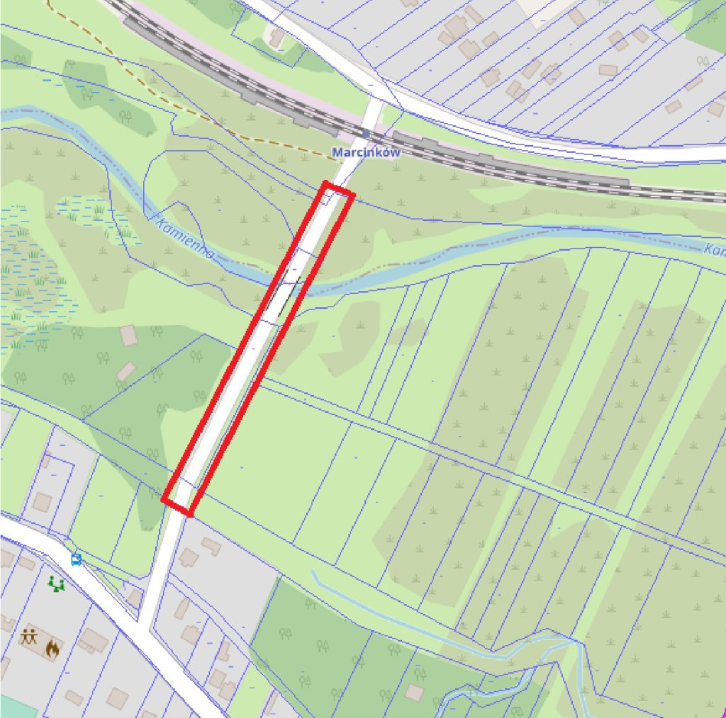 Mapa przedstawiająca okolice Marcinkowa, na której zaznaczono czerwony prostokątny odcinek wzdłuż drogi i pobliskiej rzeki, otoczony polami.