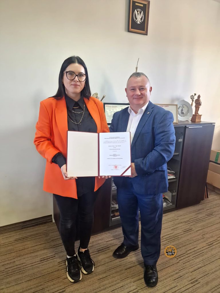 Burmistrz Miasta i Gminy Wąchock wręcza Patrycji Suwarze akt powołania na stanowisko Dyrektor Miejsko Gminnego Ośrodka Kultury. Oboje stoją w gabinecie urzędowym i trzymają otwarty dokument z pieczęcią, pozując do zdjęcia.