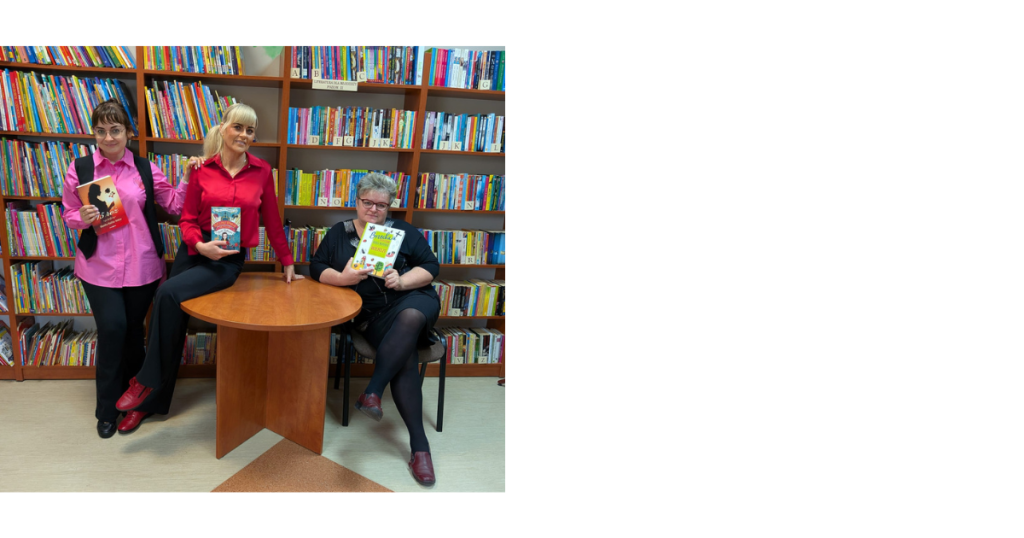 Trzy kobiety pozują w bibliotece na tle regałów wypełnionych książkami. Każda z nich trzyma w dłoniach inną książkę, prezentując jej okładkę. Kobiety są uśmiechnięte, ubrane w kolorowe koszule (różową i czerwoną) oraz czarną sukienkę.